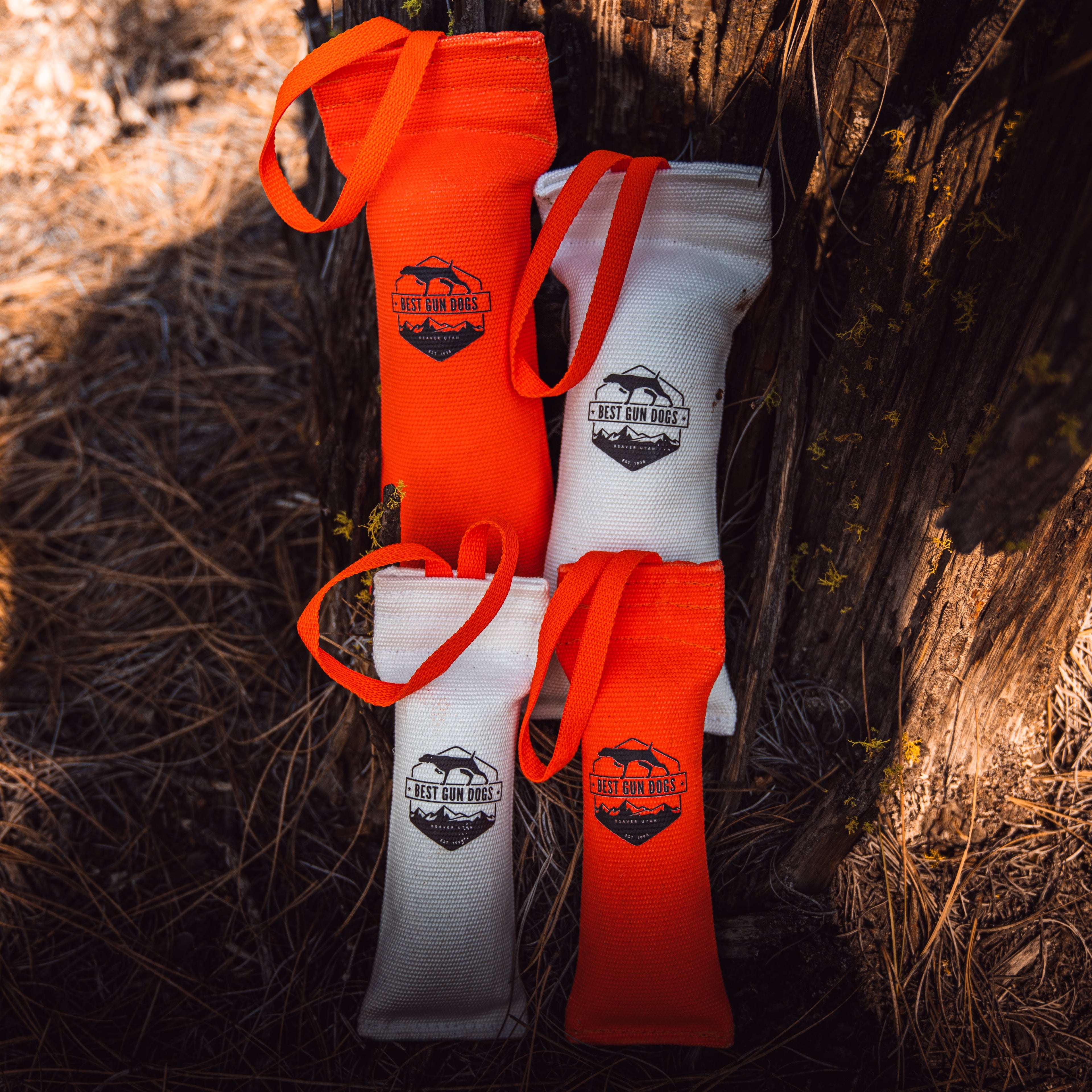 Small - Best Gun Dogs Firehose Training Dummy in orange and white rugged firehose material with throw straps on natural ground.